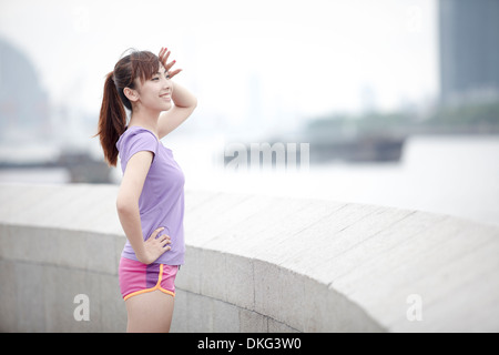 Junge weibliche Jogger von Mauer stehend Stockfoto