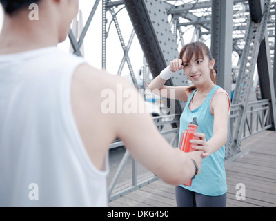 Männliche Jogger vorbei Wasserflasche, weibliche Begleitung Stockfoto