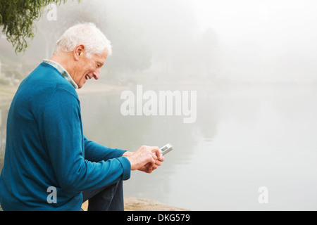 Ältere Mann lächelnd an Text auf Handy Stockfoto