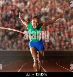 Junge Frau, die durch die Gewinner-Band im Stadion sprinten Stockfoto