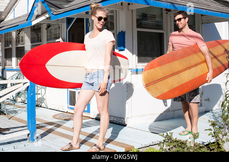 Paar auf Terrasse mit Surfbrettern, Breezy Point, Queens, New York, USA Stockfoto