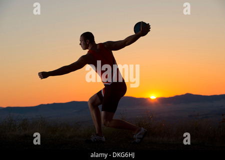 Junger Mann bei Sonnenuntergang Diskuswurf wird vorbereitet Stockfoto