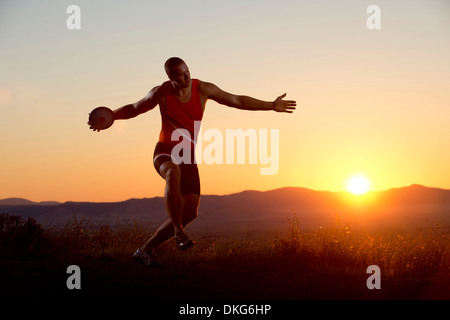 Junger Mann bereitet sich nach Sonnenuntergang Diskus werfen Stockfoto