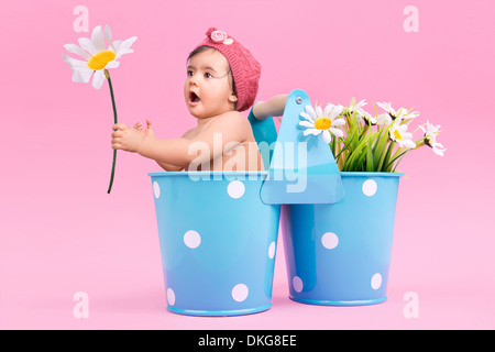 Schöne Baby in einen Eimer mit Blumen Stockfoto