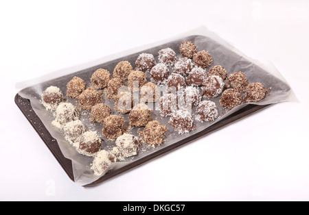 Hausgemachte Pralinen, jeder rollte in einen speziellen Belag, angeordnet in Reihen auf ein Backblech legen. Stockfoto