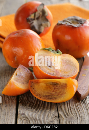 Kaki Früchte ganze und geschnittene auf einem Holztisch Stockfoto