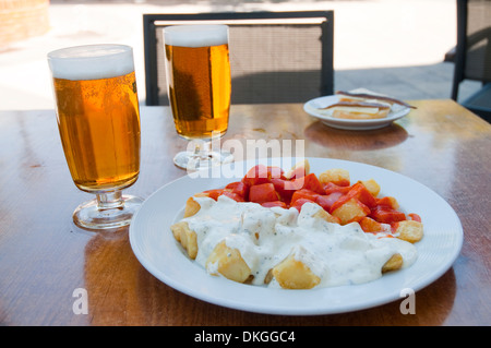 Spanische Vorspeise: Alioli Kartoffeln und Kartoffeln Bravas mit zwei Gläsern Bier auf eine Terrasse. Madrid, Spanien. Stockfoto