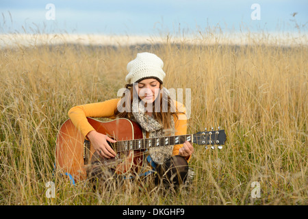 Junge Frau spielt Gitarre im Bereich Stockfoto