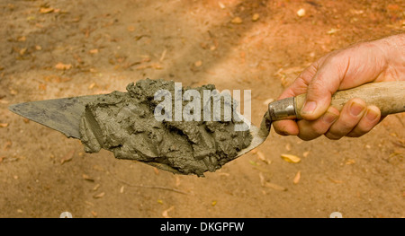 Hand, die Spitzen Maurer Kelle mit Mörtel bereit, auf Ziegelsteine gelegt werden Stockfoto