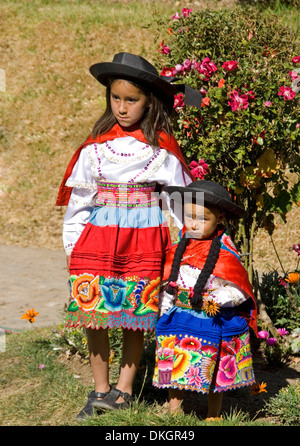 Zwei junge peruanische Mädchen gekleidet in bunter Tracht posiert für ein Foto im Dorf in den Anden in Peru Stockfoto