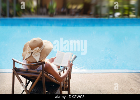 Frau lesen und entspannen in der Nähe von Luxus-Schwimmbad