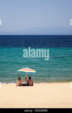 Paar unter einem Sonnenschirm am Strand von Porto Puddu, Sardinien, Italien, Mittelmeer, Europa Stockfoto