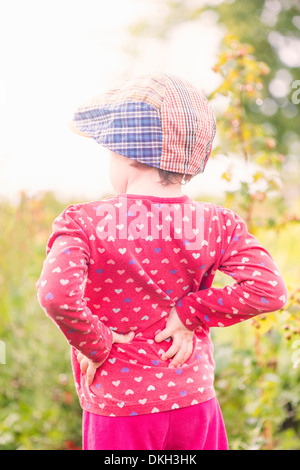 Rückansicht des jungen Kindes stehen im Garten beobachten grüne Pflanzen und Blumen Stockfoto