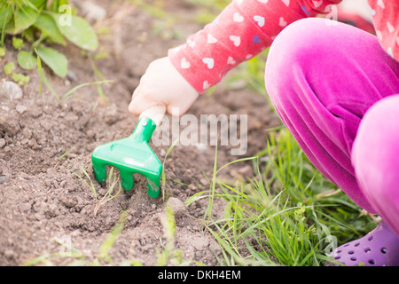 Nahaufnahme des jungen Kind im Garten mit Pflanzen und Blumen zu helfen, in den Boden graben. Stockfoto