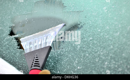 Schnee und Eis von der Auto-Windschutzscheibe kratzen Stockfoto