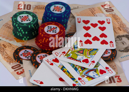 Eine Hand von Karten mit Royal Flush Pokerchips mit zehn Pfund-Noten Stockfoto