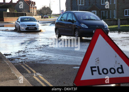 Starke Regenfälle und Stürme treffen Großbritannien, Autos werden hier gesehen, die durch Hochwasser fahren, vorbei an einem Hochwasserwarnschild. Stockfoto