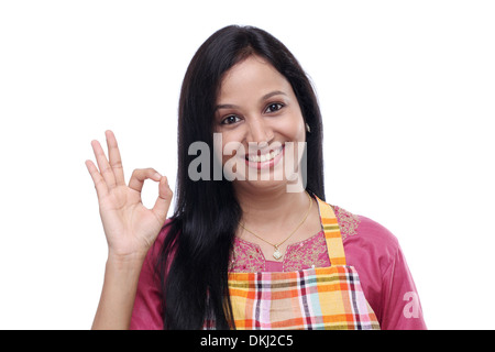Glückliche junge indische Frau trägt Küchenschürze und ok Anzeichen Stockfoto