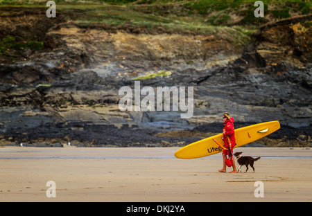 Rettungsschwimmer aus zum Surfen mit ihrem Hund auf Constantine Bay Cornwall Stockfoto