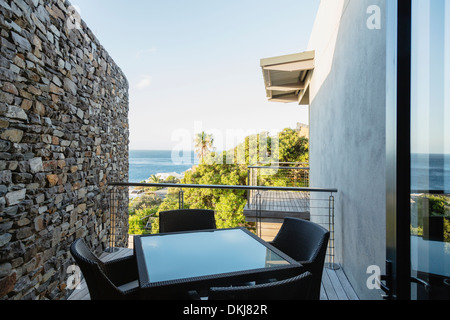 Tisch und Stühle auf Luxus-Balkon mit Blick auf Meer Stockfoto