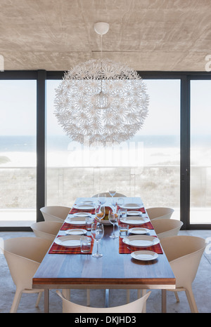 Gedeckter Tisch im modernen Speisesaal mit Blick auf Meer Stockfoto