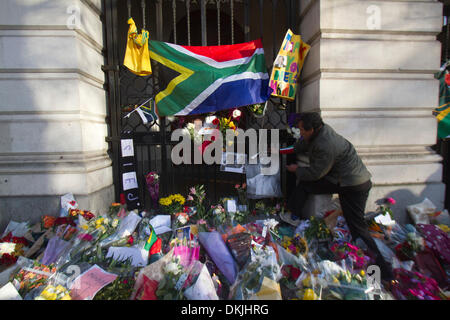 London UK. 6. Dezember 2013. Ein Mann legt eine Porträt von Nelson Mandela außerhalb der South Africa House, starb gestern im Alter von 95. Nelson Mandela wurde zum ersten schwarzen Präsidenten, ins Gefängnis geworfen wurde, nachdem er gegen die Apartheid und eine rassisch geteilte Südafrika Credit warb: Amer Ghazzal/Alamy Live-Nachrichten Stockfoto