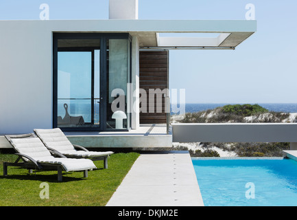 Liegestühle und lap Pool draußen modernes Haus mit Blick auf Meer Stockfoto