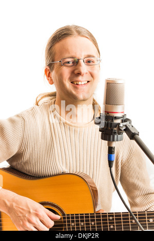 Gitarrist sitzt hinter einem Mikrofon und spielt akustische Gitarre (Serie mit dem gleichen Modell verfügbar) Stockfoto