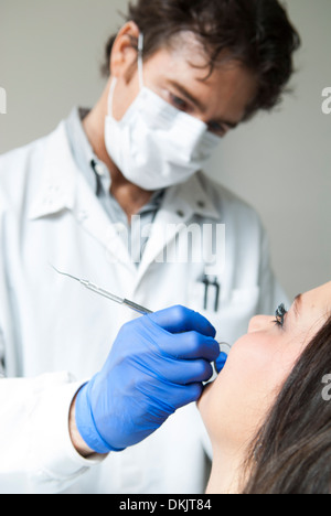 Männliche Zahnarzt tragen blaue Handschuhe Prüfung lächelnd dental Patientin Stockfoto