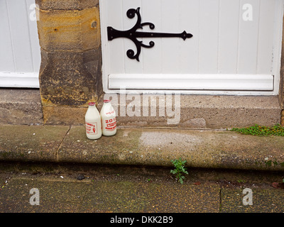 Zwei Flaschen Milch vor der Haustür eines historischen Hauses in Corbridge, Northumberland Stockfoto