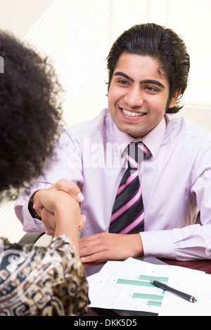 Junge indische Mann schüttelt die Hand mit Frau Stockfoto