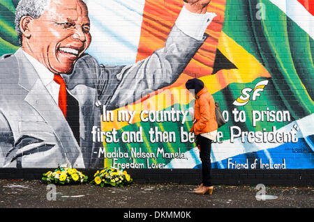 Belfast, Nordirland. 7. Dezember 2013 - hält eine Frau floral Hommagen an Mandela Wandbild nach dem Tod von Nelson Mandela am 5. Dezember links anzuschauen. Bildnachweis: Stephen Barnes/Alamy Live-Nachrichten Stockfoto