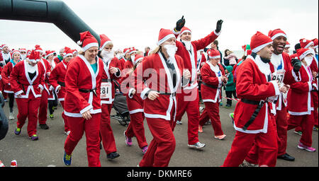 Brighton, East Sussex, UK. 7. Dezember 2013. Weihnachtsmänner zu Beginn des Santa Dash. Hunderte von Läufer aller Altersgruppen, einige Vierbeiner, einige noch nicht aus einem Kinderwagen, verkleiden sich als Weihnachtsmann zur Teilnahme an der jährlichen 5 k Santa Dash laufen entlang der Strandpromenade in Brighton & Hove. Foto © Julia Claxton Credit: Julia Claxton/Alamy Live News Stockfoto