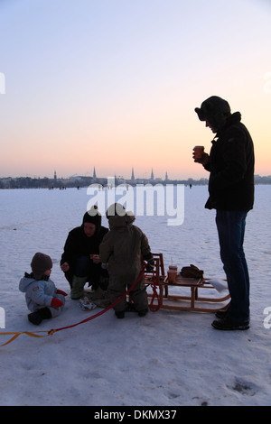 Familie mit Schlitten auf gefrorenen See Außenalster (Außenalster) im Winter, Hanse Stadt Hamburg, Deutschland Stockfoto