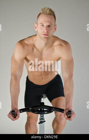 Attraktive junge Mann trainieren im Fitnessstudio: Spinnen auf Heimtrainer Stockfoto