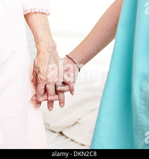 Pflegeperson faltig Händchenhalten senior Frau zu Hause Stockfoto