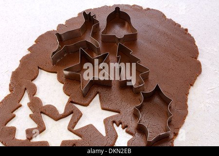 Ausstechformen und ausgeschnittenen Formen auf Lebkuchenteig - Stern, Rentier, Weihnachtsbaum, Holly Blatt- und Glocke Stockfoto