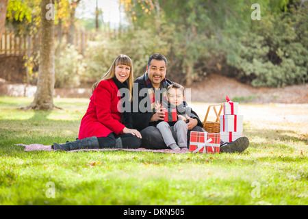Junge gemischte Rasse Familie genießen Weihnachtsgeschenke im Park zusammen. Stockfoto