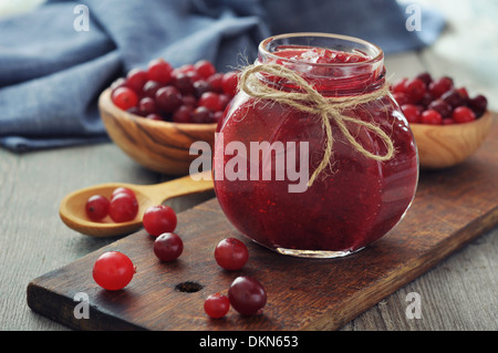 Preiselbeermarmelade in Glas mit frischen Beeren auf hölzernen Hintergrund Stockfoto