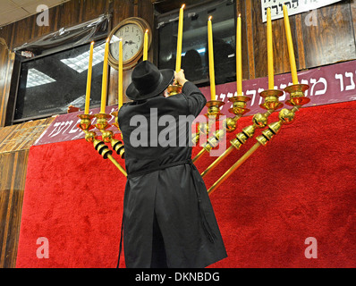 Eine orthodoxe jüdische Rabbiner zündet Hanukkah Kerzen als Studenten und Gemeindemitglieder Watch Lubawitsch Hauptquartier in Brooklyn, New York Stockfoto