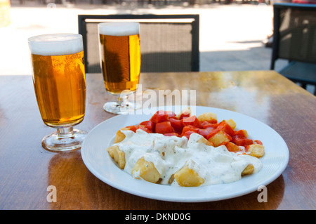 Spanische Vorspeise: Alioli Kartoffeln und Kartoffeln Bravas mit zwei Gläsern Bier auf eine Terrasse. Madrid, Spanien. Stockfoto