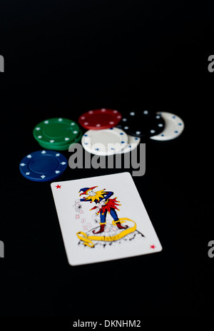 Joker Spielkarte und Poker-Chips auf einem schwarzen Hintergrund Stockfoto