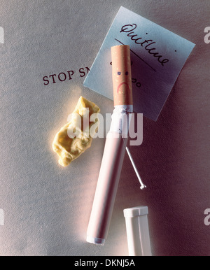 Eine Zigarette mit einem traurigen Gesicht und eine Akupunkturnadel und Nicotene patch am Gummi zu Nikotin und Rauchen kit beenden. Beihilfen, die mit dem Rauchen aufhören Stockfoto