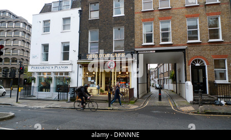 Ein Mann, der entlang der Guilford Street am Café Trio D'Or vorbeiradelt Von Brownlow Mews in West London WC1 England GB KATHY DEWITT Stockfoto