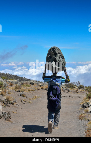 Ein Portier zu Fuß über den Wolken auf der Durchreise der Moorland-Zone auf seine Abstammung vom Kilimanjaro Marangu-route Stockfoto