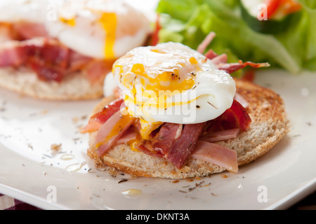 Pochiertes Ei auf Toast mit geräuchertem Speck und Salat Stockfoto