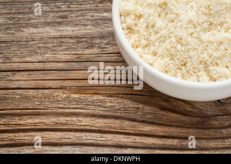 Mandel Mehl hoher Proteingehalt, wenig Kohlenhydrate, wenig Zucker und Gluten-frei - eine Keramikschale auf gemasertem Holz Hintergrund Stockfoto