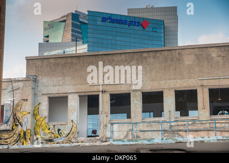Tel Aviv, Israel. Eine verlassene Ruine vor einem modernen Hochhaus mit dem Logo der "Bank HaPoalim" ("Arbeiter-Bank") / Stockfoto