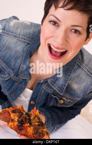 Eine sehr aufgeregte Frau genießt eine oberste Fleisch knusprige pizza Stockfoto