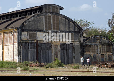 Ein Mann und eine Frau gehen vorbei an einem alten Gebäude am verlassenen Bahnhof in Battambang, Kambodscha. Stockfoto